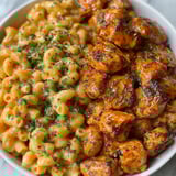 A plate of food with mac and cheese and chicken.
