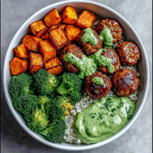 A bowl of meatballs with a green sauce and a side of broccoli.