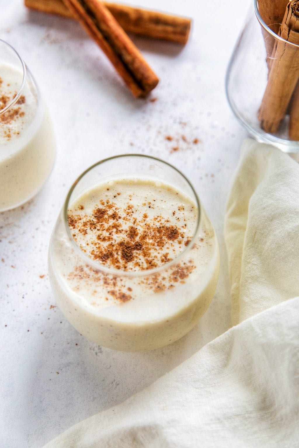 A glass of eggnog with cinnamon on top.