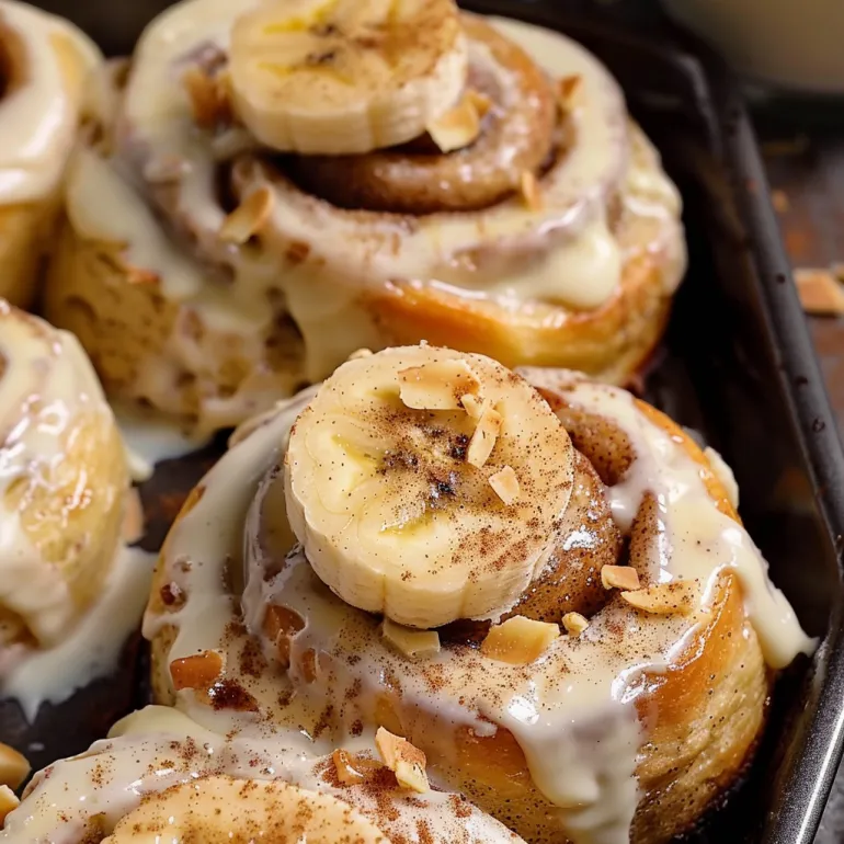 A tray of cinnamon rolls with bananas on top.