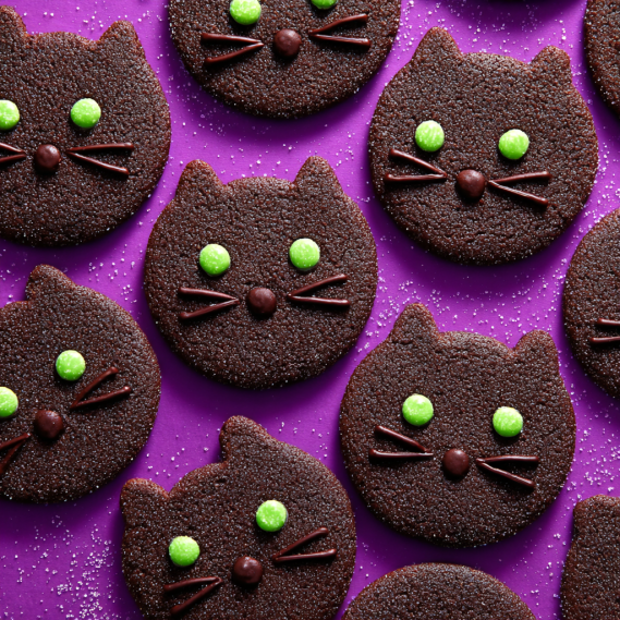 A purple table with chocolate cat cookies.