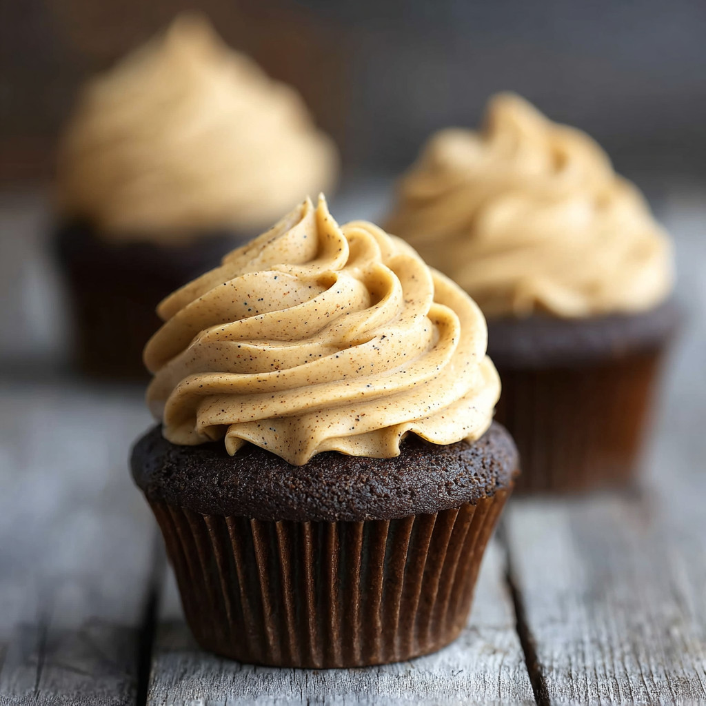 Three cupcakes with frosting and nuts.